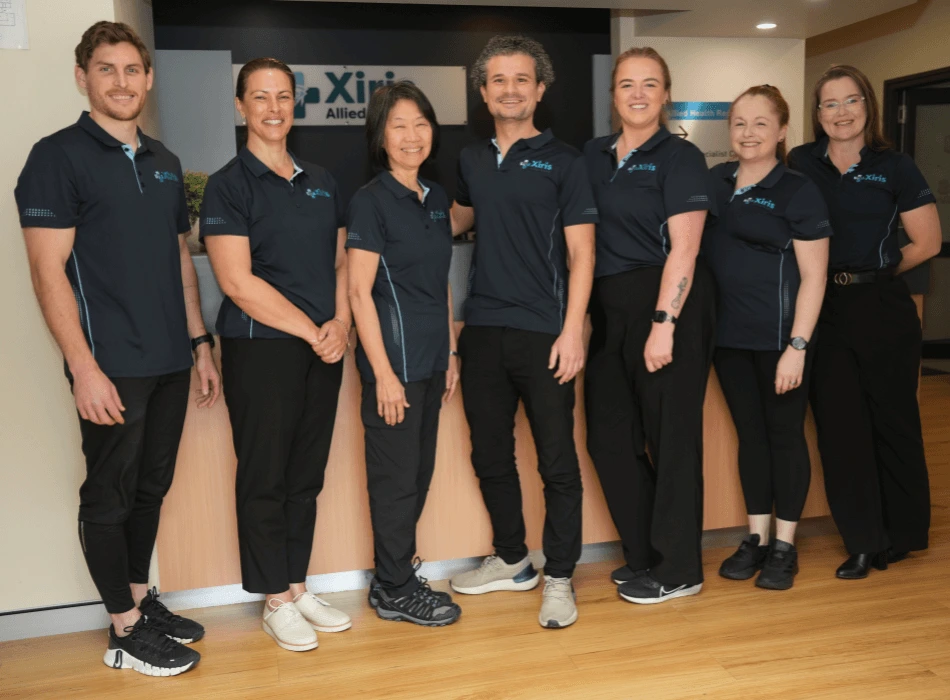 Team of clinicians in uniform standing in the lobby at Xiris Allied Health.